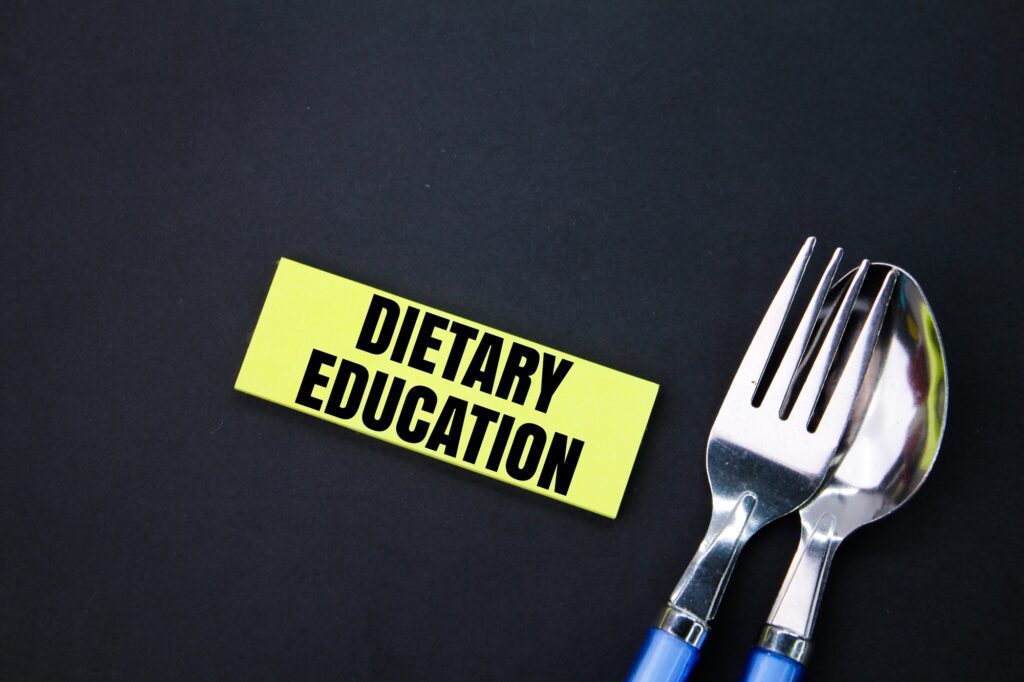 spoon, fork and paper colored with the word dietary education.